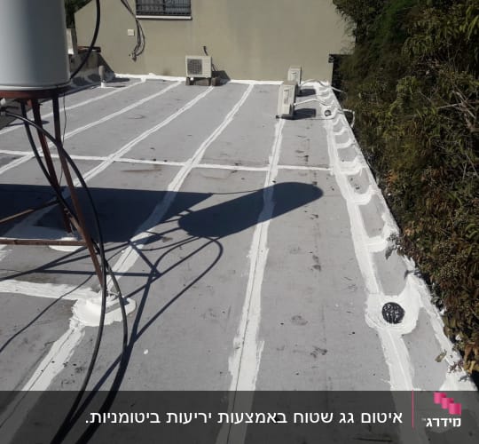 איטום גג עם חומר לבן לאורך התפרים